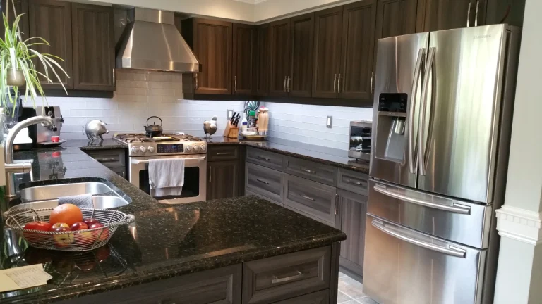 Dark tuxedo five-piece door kitchen reface featuring a chef style range hood in a Burlington home.