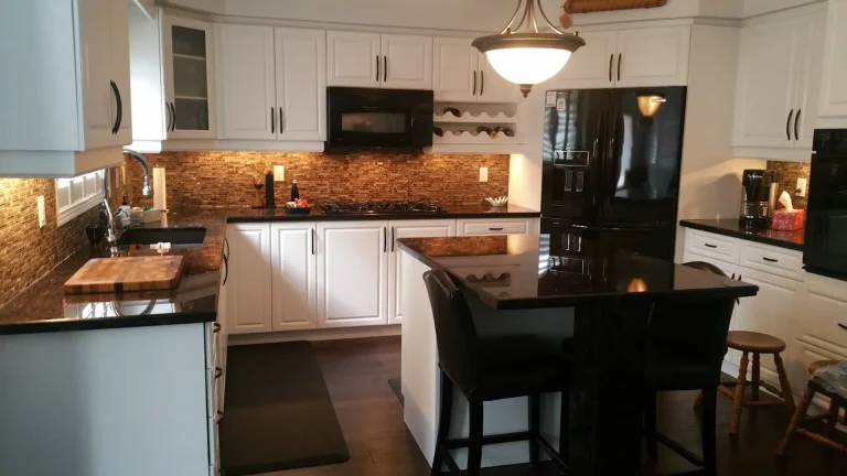 Seamless white cabinet doors with modern black handles are paired with contrasting black countertops and dark floors.