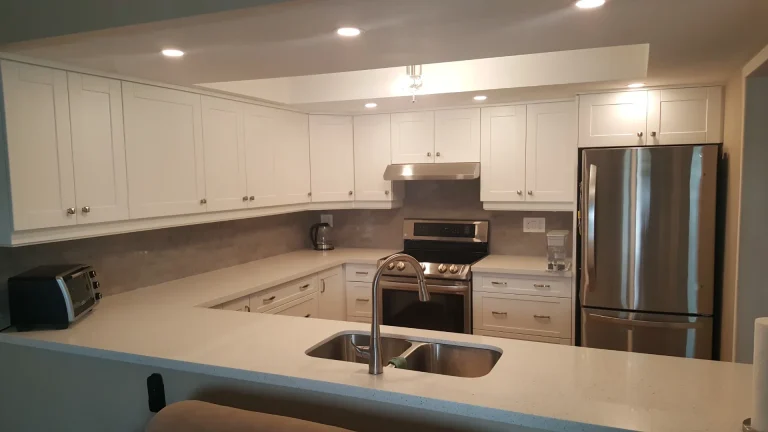Open galley-style kitchen in Tyandaga with white shaker doors and quartz surfaces.