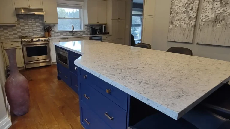 The transformed kitchen features a bold navy island with microwave integration and Chantilly White cabinets.