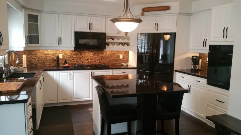 White seamless door cabinet reface in a Dundas home featuring black granite countertops and an island with seating.